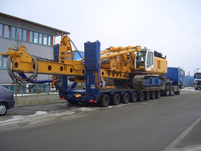 Schwertransport-LKW mit gelber Baumaschine auf Tieflader